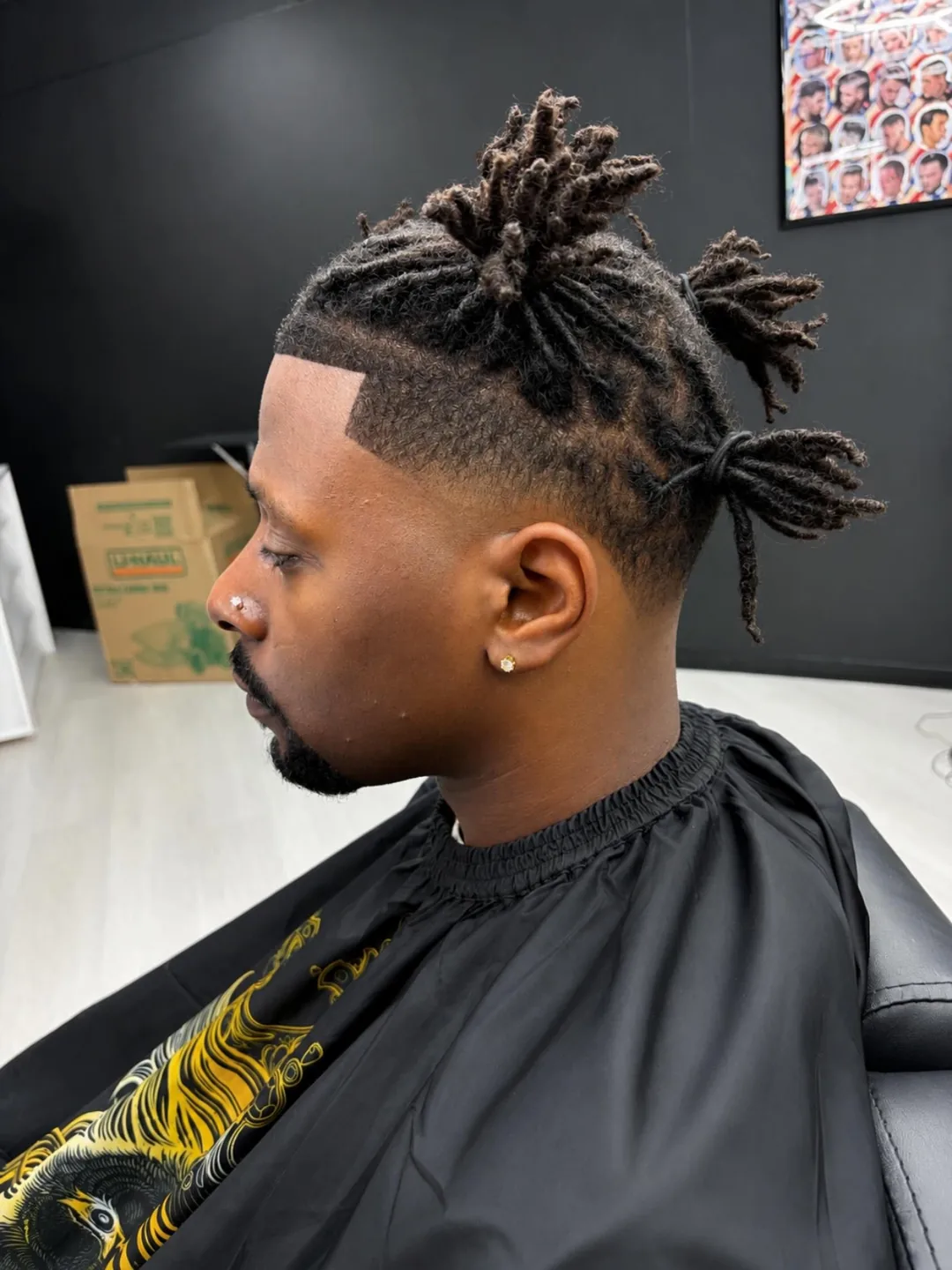 Side-profile haircut with twisted locs and a sharp fade in a barbershop chair